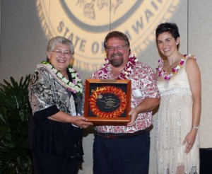 David Fisher (center) receives the Mayor's Community Service Award from Mayor Charmaine Tavares (L) and Economic Development Coordinator Deidre Tegarden (R). Photo by: Sheryl Saphore Photography
