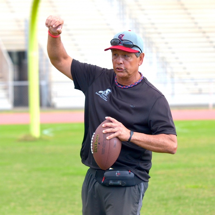 Saint Louis School coach Vince Passas explains the proper release to a group of quarterbacks Saturday at War Memorial Stadium. Photo by Rodney S. Yap.