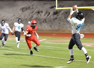 King Kekaulike's Brandon Soriano (22) squeezes this pass from quarterback Cameron Russell (5). Photo by Rodney S. Yap.
