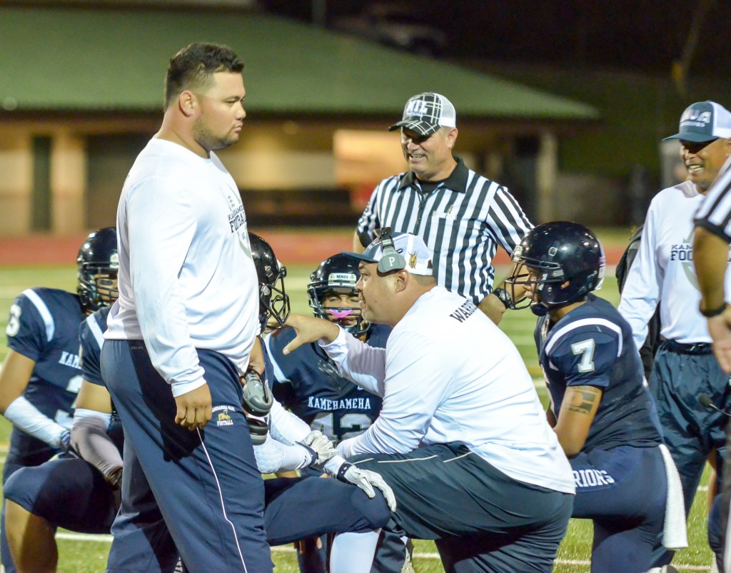 Kamehameha Maui's defensive coordinator Trenson Himalaya (standing) and linebackers coach Mark Vaught talks to the defense during a second-half injury time out Friday. Photo by Rodney S. Yap.