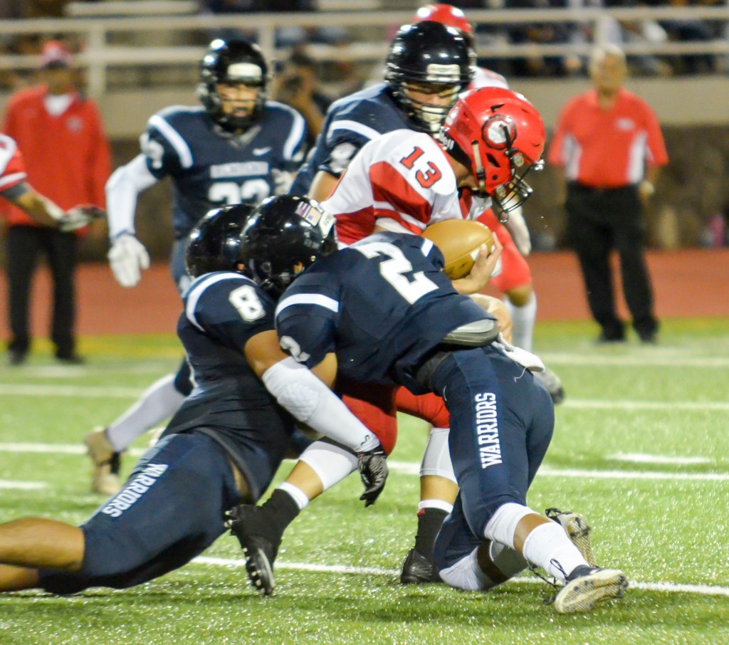 Kamehameha Maui's Mike Kahula (8) and Kamuela Kaniaupio (2) sandwich Lahainaluna quarterback Dylan Delatori. Photo by Rodney S. Yap.