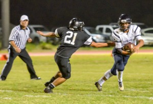 Kamehameha Maui quarterback Kainoa Sanches manages to avoid the grasp of King Kekaulike's Rilee Peters. Photo by Rodney S. Yap.