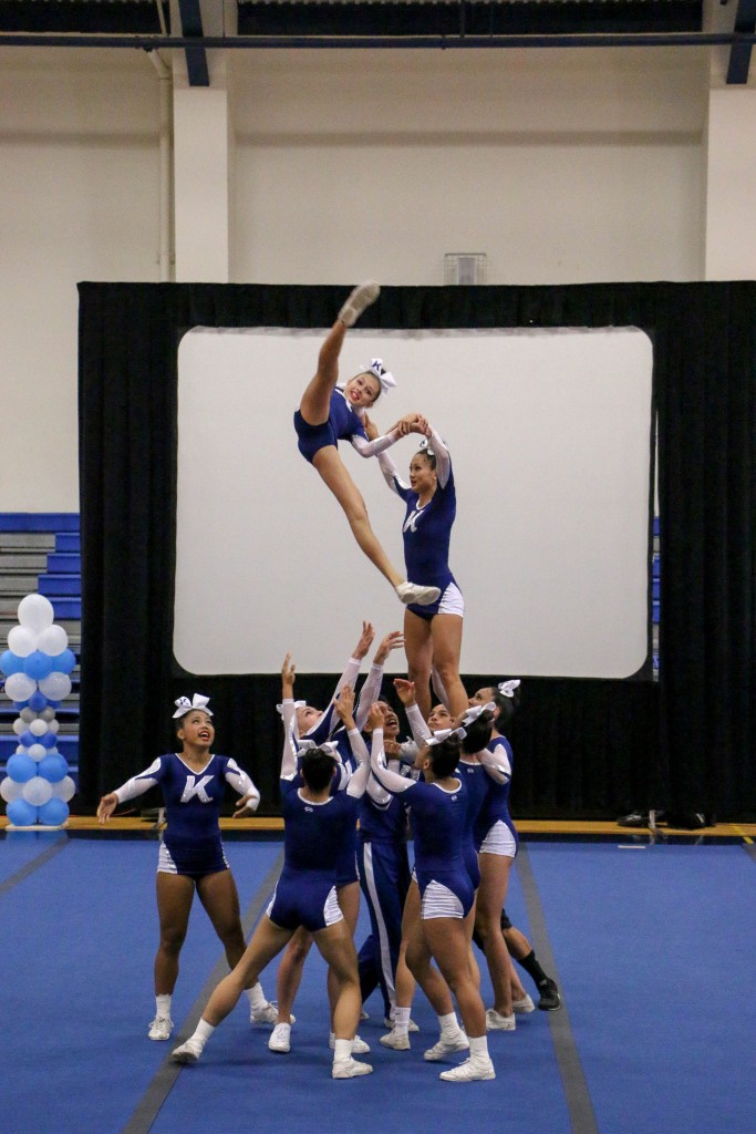 Chloe Lawrence goes through a switch kick straddle transition from a smush to an arabesque assisted by her teammate Ashlee Sawai (elevated) and the rest of her team.