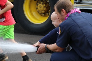 Trucker Dukes shooting water with his dad, firefighter Joshua Dukes outside of the Kahului Fire Station. Photo by Wendy Osher.