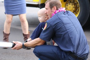 Trucker Dukes shooting water with his dad, firefighter Joshua Dukes outside of the Kahului Fire Station. Photo by Wendy Osher.