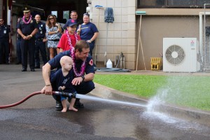 Trucker Dukes shooting water with his dad, firefighter Joshua Dukes outside of the Kahului Fire Station. Photo by Wendy Osher.