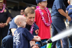 Trucker Dukes shooting water with his dad, firefighter Joshua Dukes outside of the Kahului Fire Station. Photo by Wendy Osher.