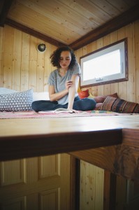 Island Tiny Homes, Viva Wittman reading in the loft bedroom space Photo credit: Kailea Sonrisa, www.harnessyourbreath.com