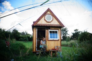 Jen Chalupsky in the entrance of an Island Tiny Home. Photo credit: Kailea Sonrisa, www.harnessyourbreath.com