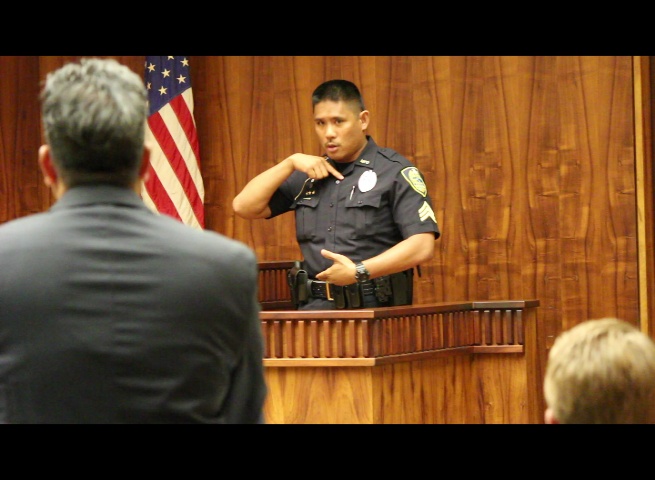 Maui Police Detective Gordon Sagun shows the length of a wound sustained by one of the stabbing victims as prosecuting attorney Robert Rivera looks on.
