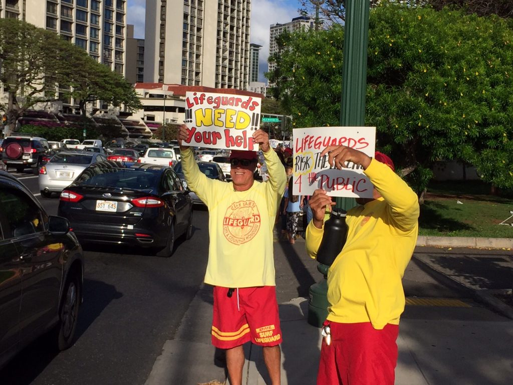 Hawaii Government Employees Association Unit 14 members (ocean/water safety and state law enforcement officers) and their supporters waved signs and rallied on Monday, May 9, along Ala Moana Blvd in a show of solidarity for their colleagues on Maui. The sign wavers are urging the Maui County Council to pass funding legislation for the Unit 14 arbitration decision that was finalized and awarded by an arbitration panel on February 22 of this year. Courtesy photo.