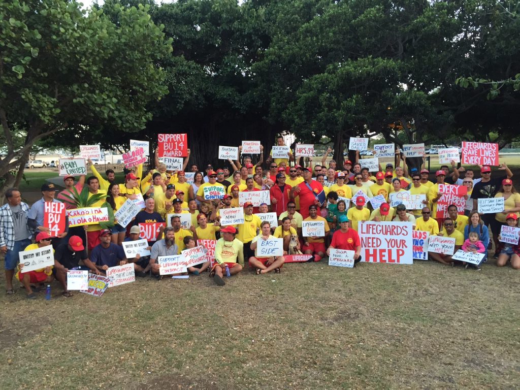Hawaii Government Employees Association Unit 14 members (ocean/water safety and state law enforcement officers) and their supporters waved signs and rallied on Monday, May 9, along Ala Moana Blvd in a show of solidarity for their colleagues on Maui. The sign wavers are urging the Maui County Council to pass funding legislation for the Unit 14 arbitration decision that was finalized and awarded by an arbitration panel on February 22 of this year. Courtesy photo.