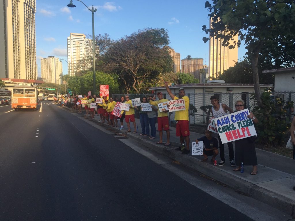 Hawaii Government Employees Association Unit 14 members (ocean/water safety and state law enforcement officers) and their supporters waved signs and rallied on Monday, May 9, along Ala Moana Blvd in a show of solidarity for their colleagues on Maui. The sign wavers are urging the Maui County Council to pass funding legislation for the Unit 14 arbitration decision that was finalized and awarded by an arbitration panel on February 22 of this year. Courtesy photo.