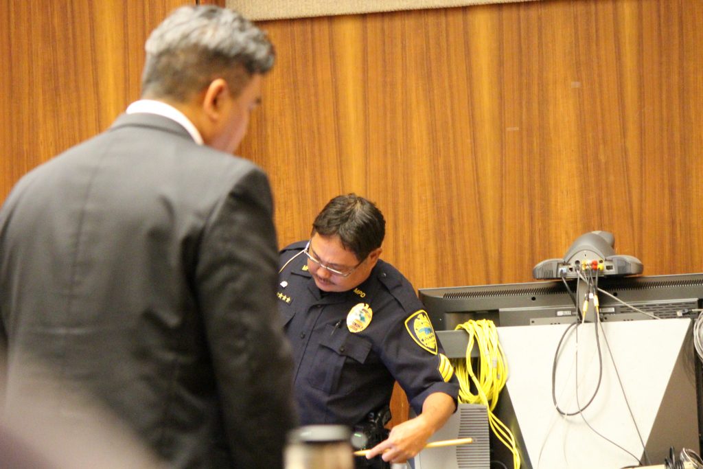 Sgt. Wendell Loo pointing to a photo of injury marks on on the defendant's hands (6.29.16) Photo by Wendy Osher.