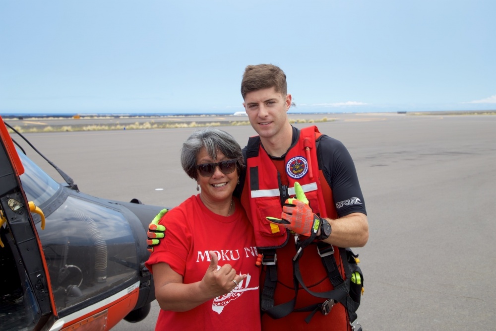 A Coast Guard rescue swimmer involved in the rescue stands with the mother of Sidney Uemoto following her daughter's rescue nine miles off Kona, Hawaii, July 15, 2016. Uemoto and David McMahon were both rescued by a Coast Guard MH-65 Dolphin helicopter crew following an expansive joint search by Navy, Royal New Zealand air force, U.S. Air Force and Coast Guard crews. (U.S. Coast Guard photo by Lt. Cmdr. Kevin Cooper/Released)