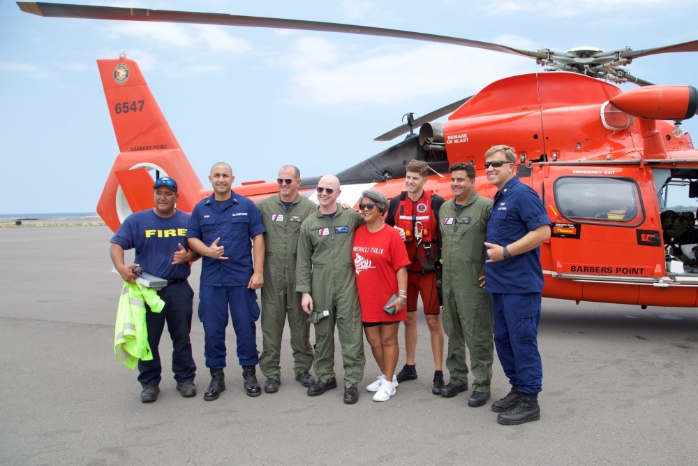 Coast Guard and Hawaii Fire Department personnel stand with the mother of Sidney Uemoto following her daughter's rescue nine miles off Kona, Hawaii, July 15, 2016. Uemoto and David McMahon were both rescued by a Coast Guard MH-65 Dolphin helicopter crew following an expansive joint search by Navy, Royal New Zealand air force, U.S. Air Force and Coast Guard crews. (U.S. Coast Guard photo/Released)