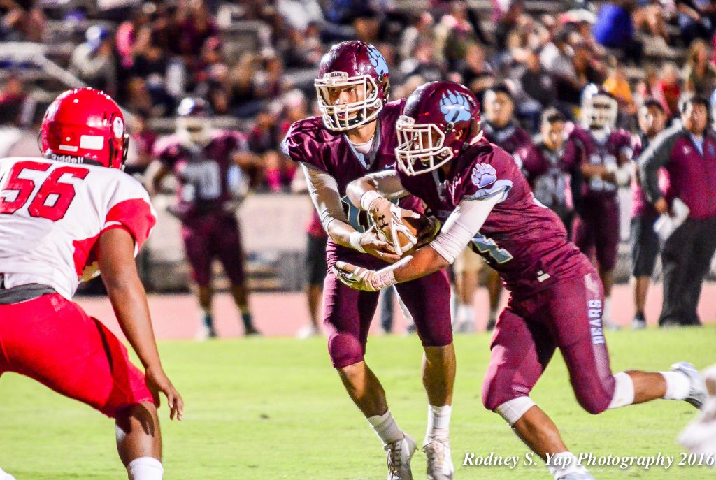 Baldwin High School quarterback Chayce Akaka prepares to fake a handoff to Daniel Corpuz and keep the ball as Lahainaluna's Viliami Hafoka looks on. Photo by Rodney S. Yap.