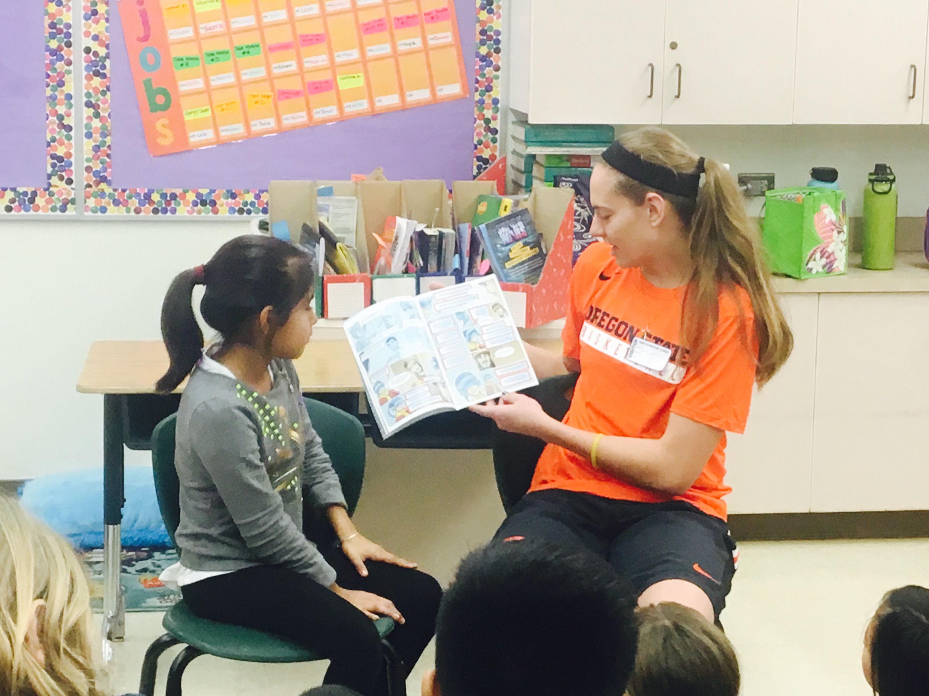 OSU’s visit to Kīhei Elementary player #24 senior Sydney Wiese reading comic book to class. PC: basketballMAUI