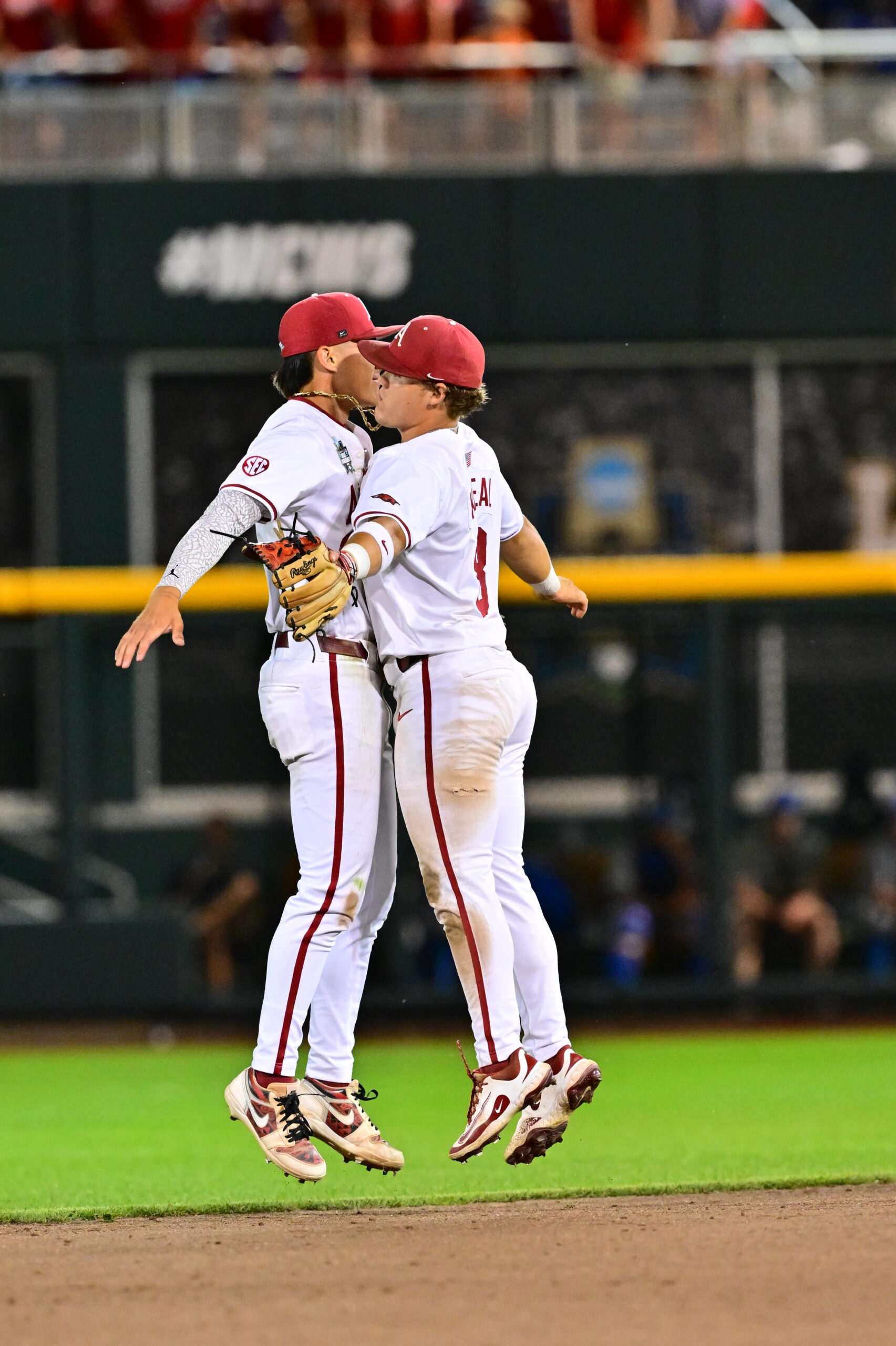 University of Arkansas shorts Wehiwa Aloy (left) and second baseman Cam Kozeal chest bump during the Razorbacks' 7-3 win over UCLA on June 17, 2025. JACKSON LEICHNER / University of Arkansas Athletic Department photo