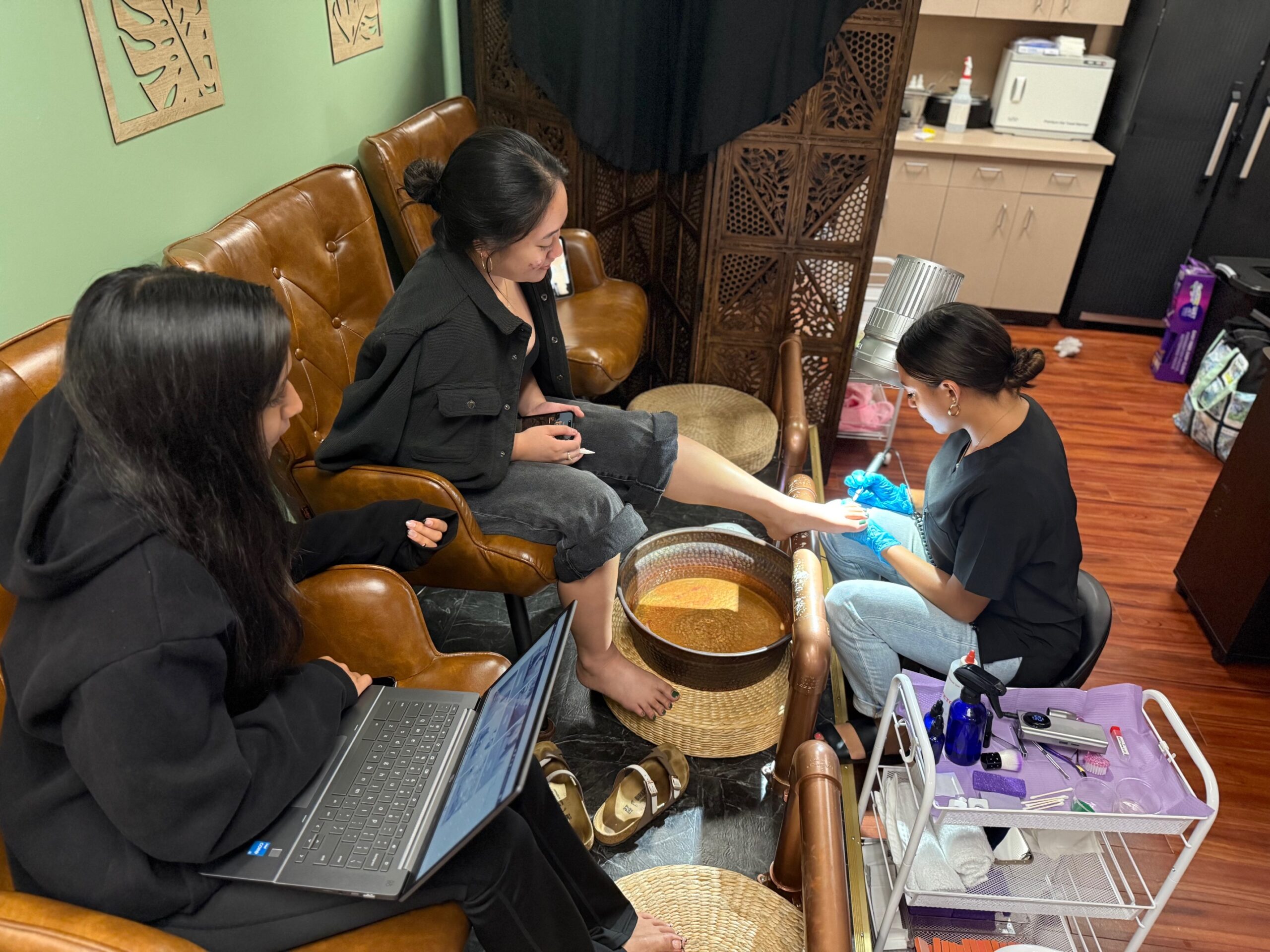From left, Kamalei Kaholokula observes a perdicure procedure being done on Jhanine Roflo Rumbaoa by Seyna Palacios on Thursday. Reese Yap photo