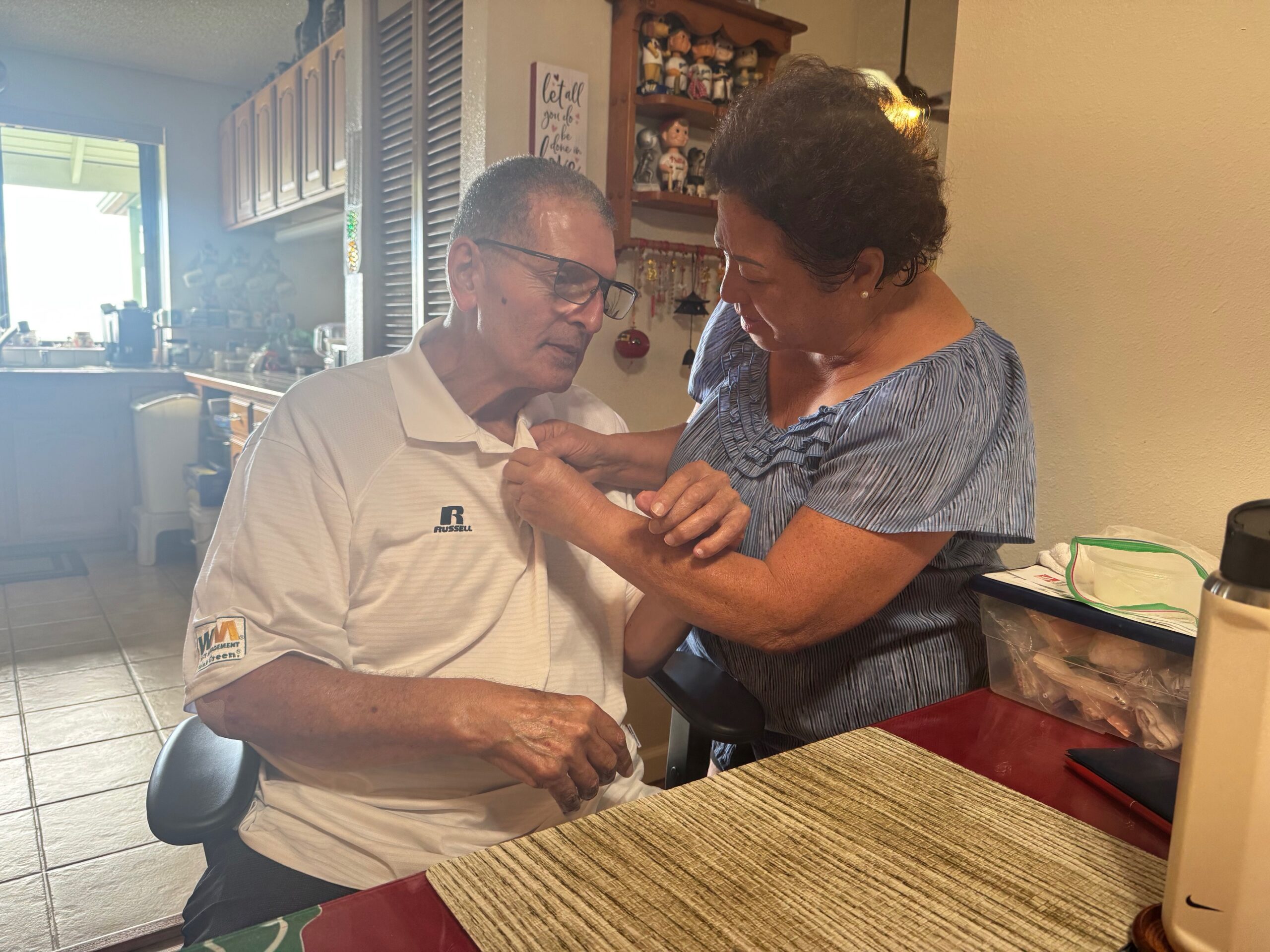 Joycelyn Victorino helps husband Mioke Victorino, the former Maui mayor, button his shirt prior to an interview on Thursday from their home in Wailuku Heights. HJI / ROB COLLIAS photo
