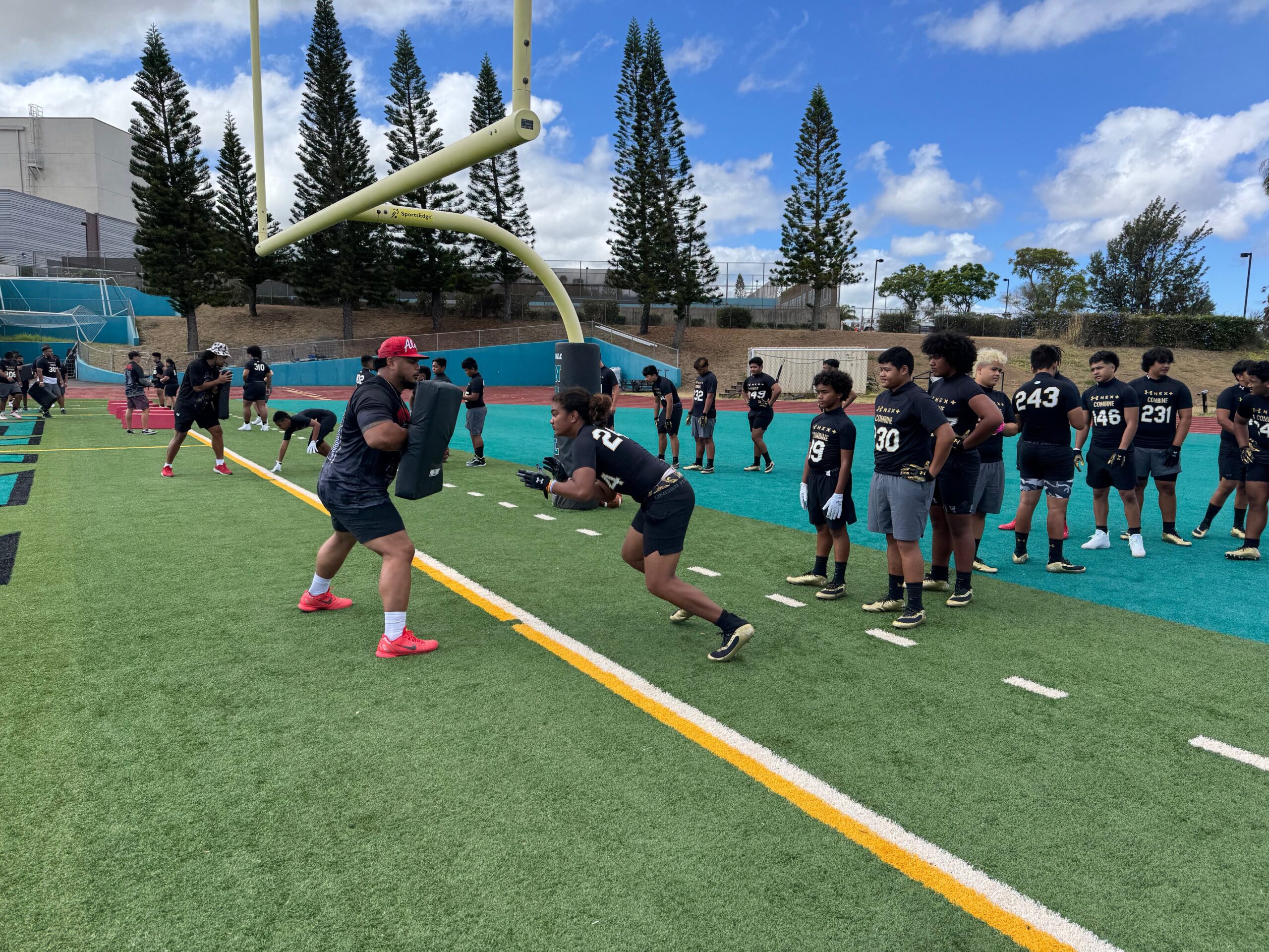 Tyson Alualu (red hat), a retired 13-year NFL defensive lineman, runs a drill on Saturday at the Under Armour Next Camp. HJI / ROB COLLIAS photo