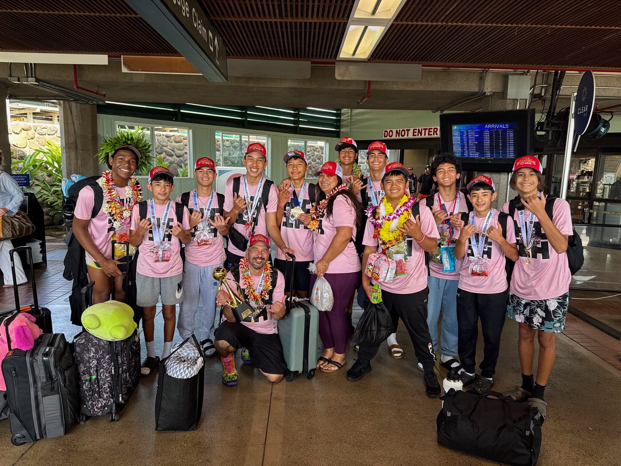 The 11-player Hawaiian Style Volleyball Club boys 15 USA Volleyball national champions pose with coaches Kalae Tanaka and Kau’ilaniku’ulei Tanaka on Monday at Kahului Airport. HJI / ROB COLLIAS photo