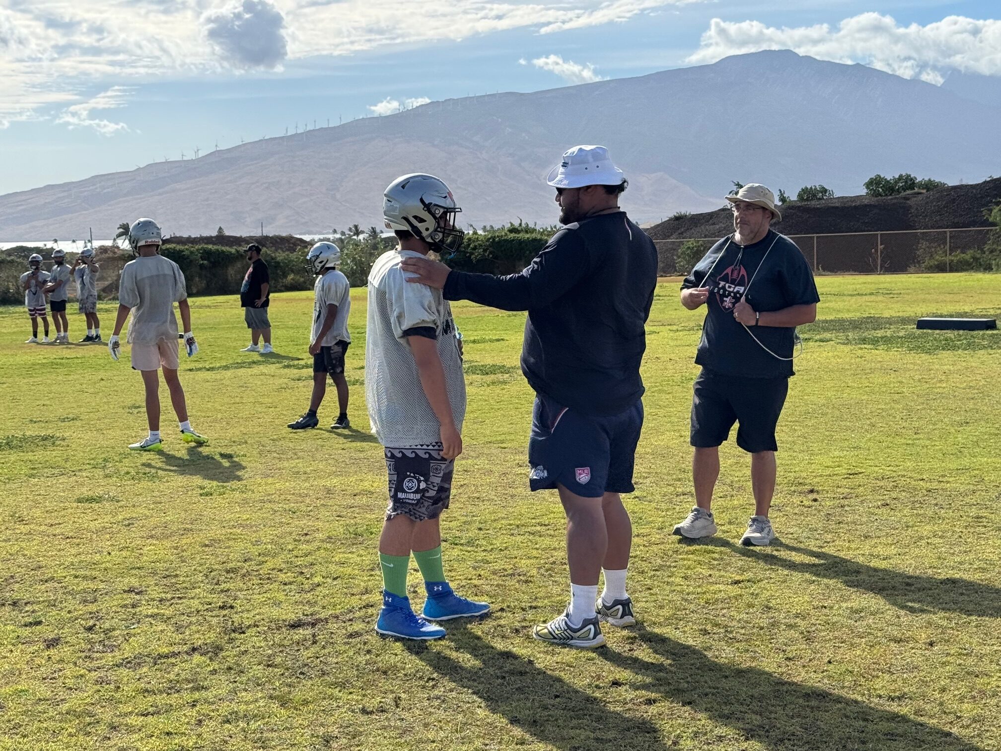 Ngalu Fusimalohi (white hat) speaks with one of his Kūlanihākoʻi High School junior varsity football players on July 24. The Manta Rays will play at the 11-player level for the first time this season. HJI / ROB COLLIAS photo