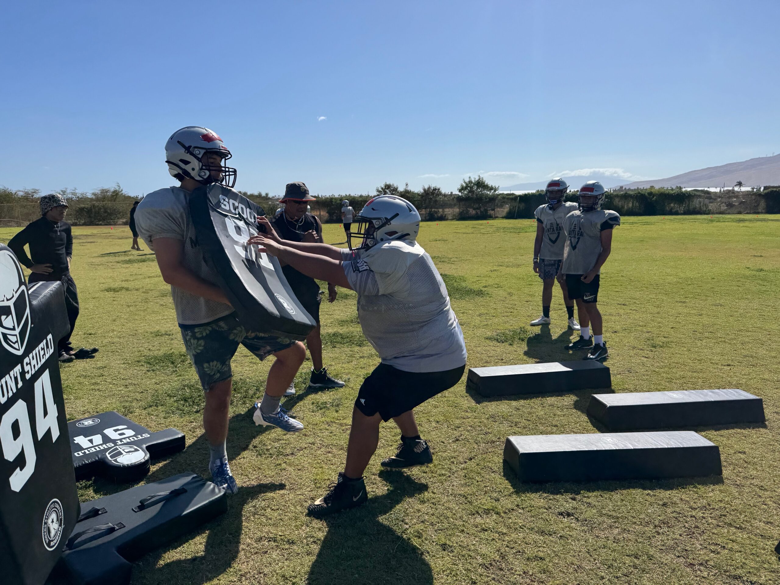 Eliaz Pe Benito (middle) runs a blocking drill as Luke Adams holds the pad at Kūlanihākoʻi High School's practice field on Aug. 1. The Manta Rays will play 11-player football for the first time this season, at the Maui Interscholastic League junior varsity level. HJI / ROB COLLIAS photo