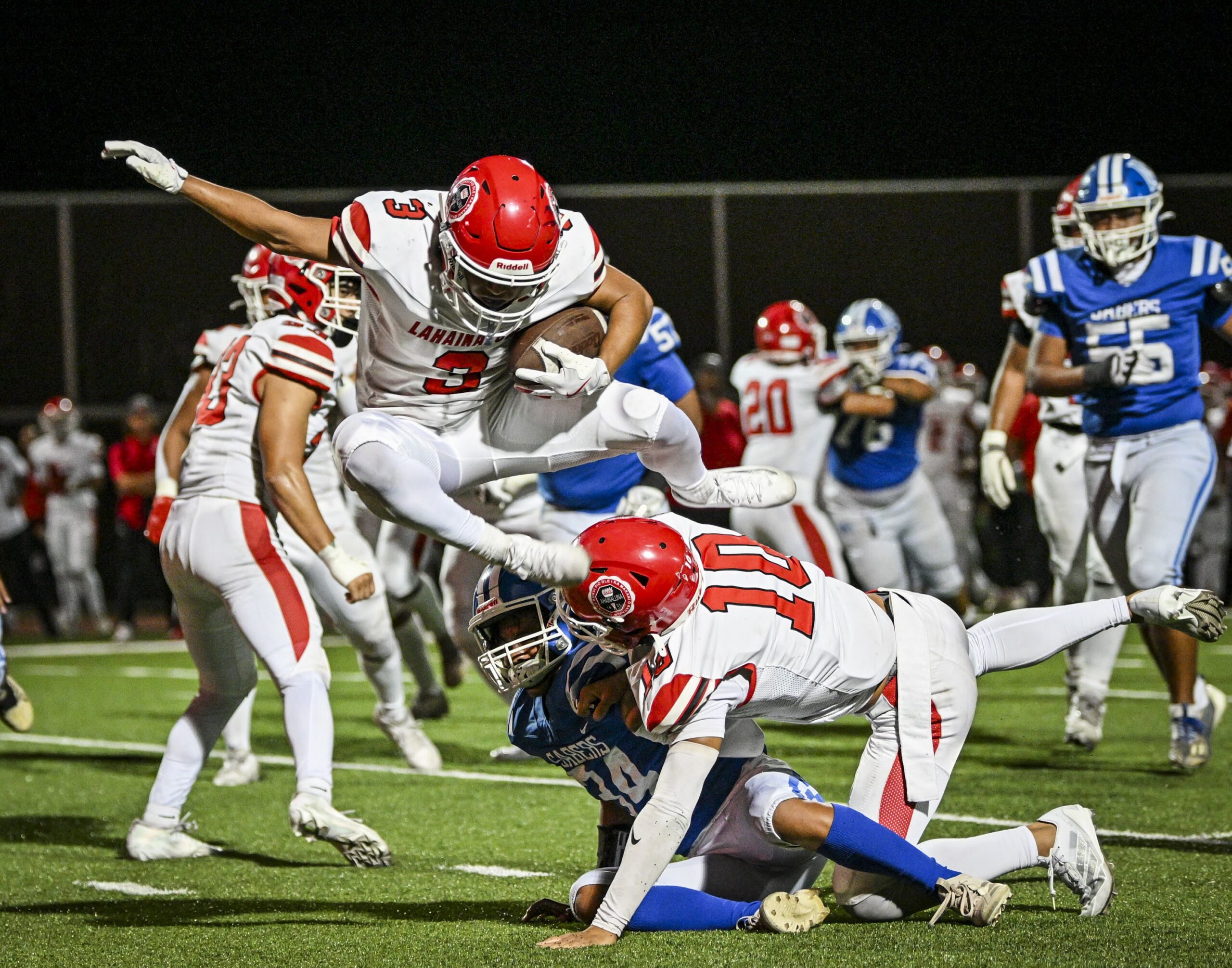 Lahainaluna High School's Joseph Arcangel lepas over teammate Maui Kanekoa-Slate (10) and Maui High's Akamu Benjamin on Saturday at Sue Cooley Stadium. The Lunas won the game 49-14. GLEN PASCUAL photo