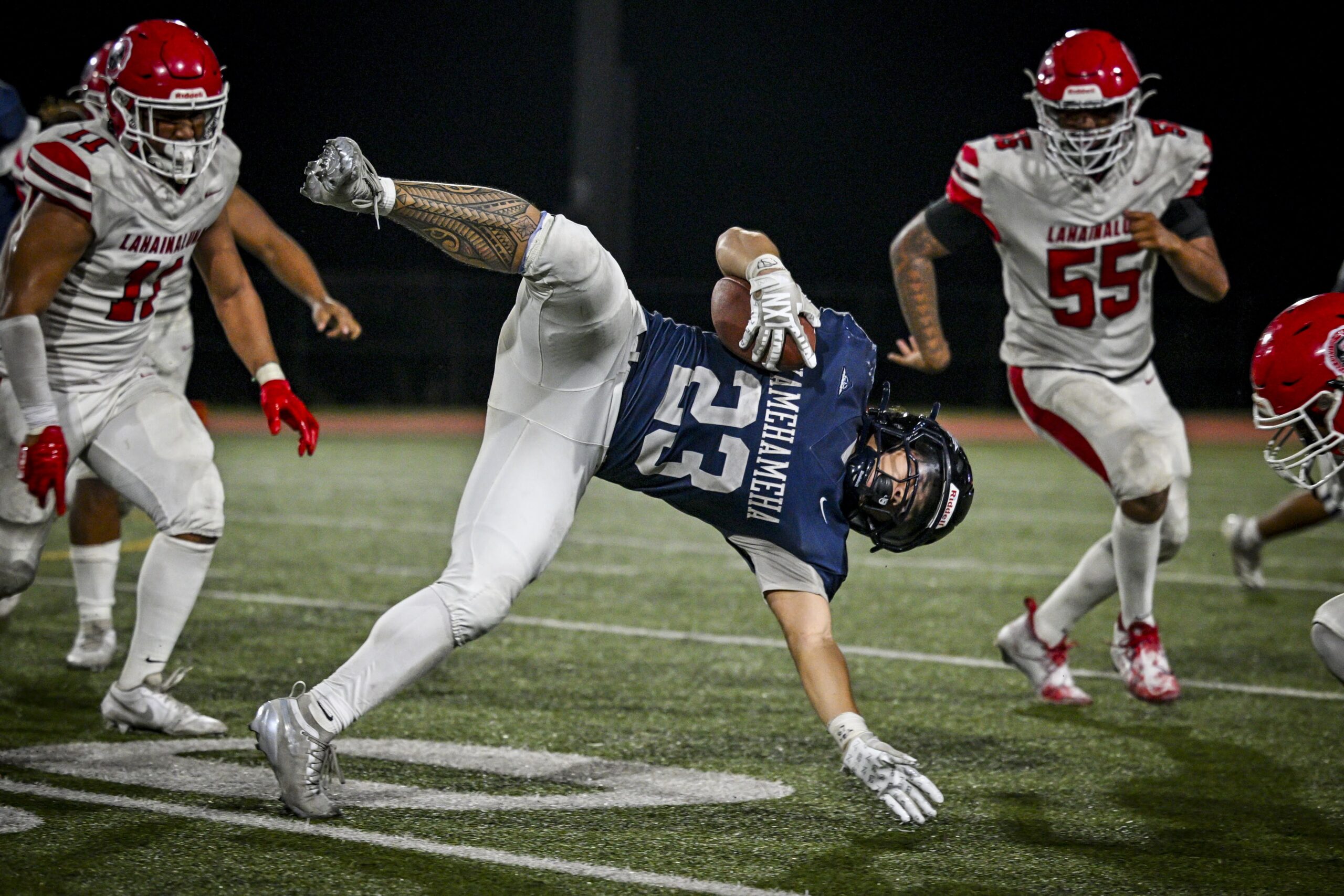 Kamehameha Maui's Nakoa Pau is upended during the Warriors' 27-7 win over Lahainaluna on Friday night. Lahainaluna's Kden Pu closes in on right. GLEN PASCUAL photo