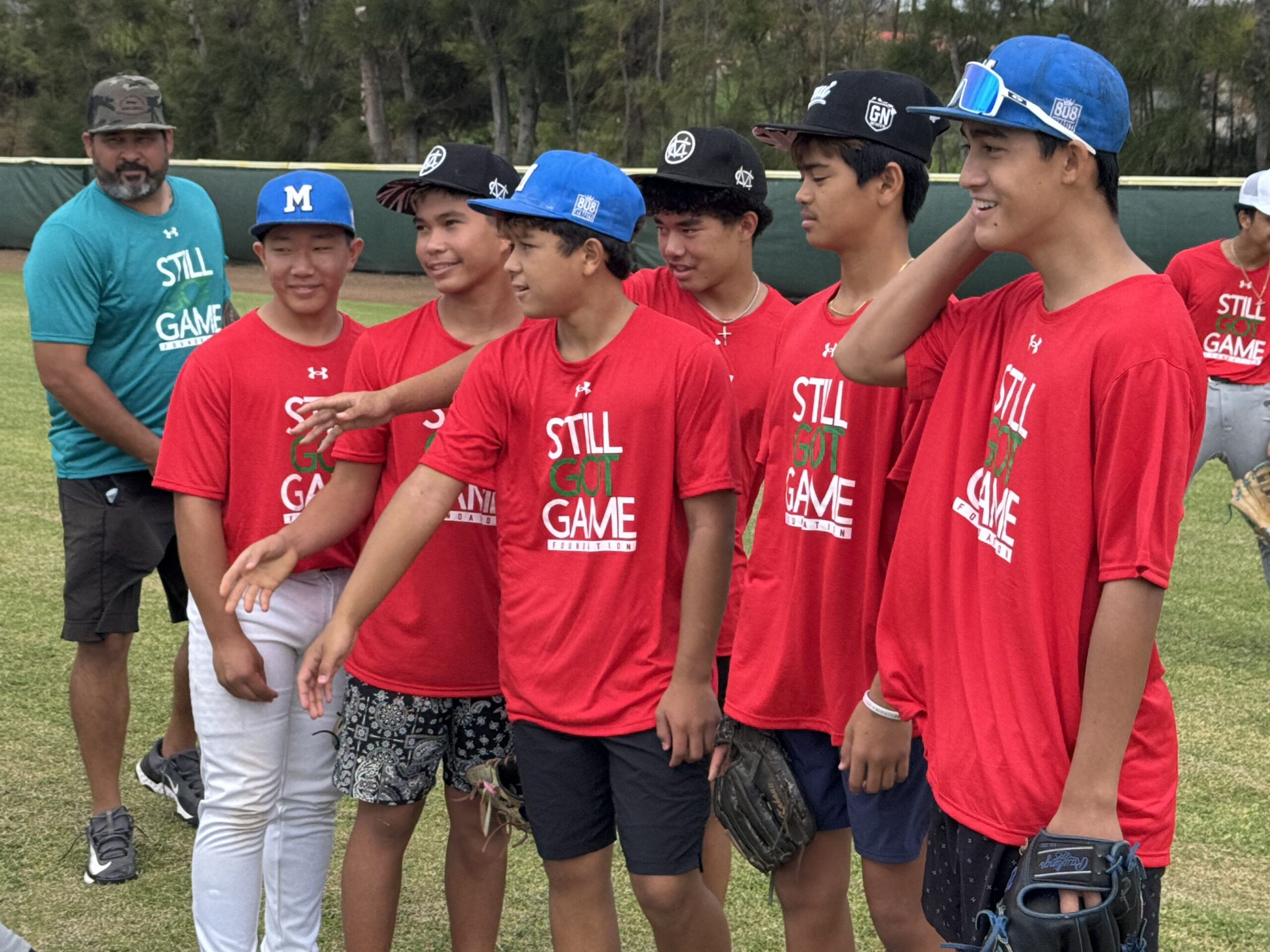 Kanekoa Texeira (left) works with youth baseball players at Maehara Stadium on Sunday. HJI / ROB COLLIAS photo