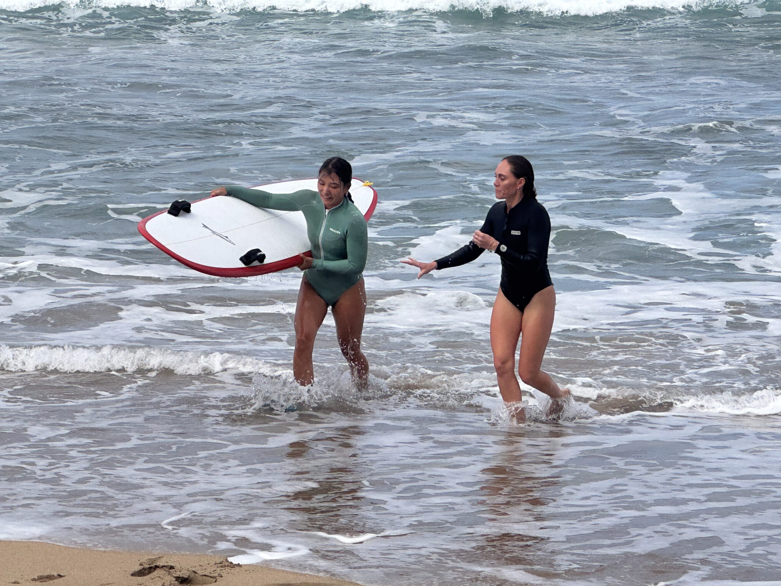 Lahainaluna assistant coaches Alyssa Kuwana and Lara Claydon come to shore after practicing practicing surfboard rescues. KIM BALL photo