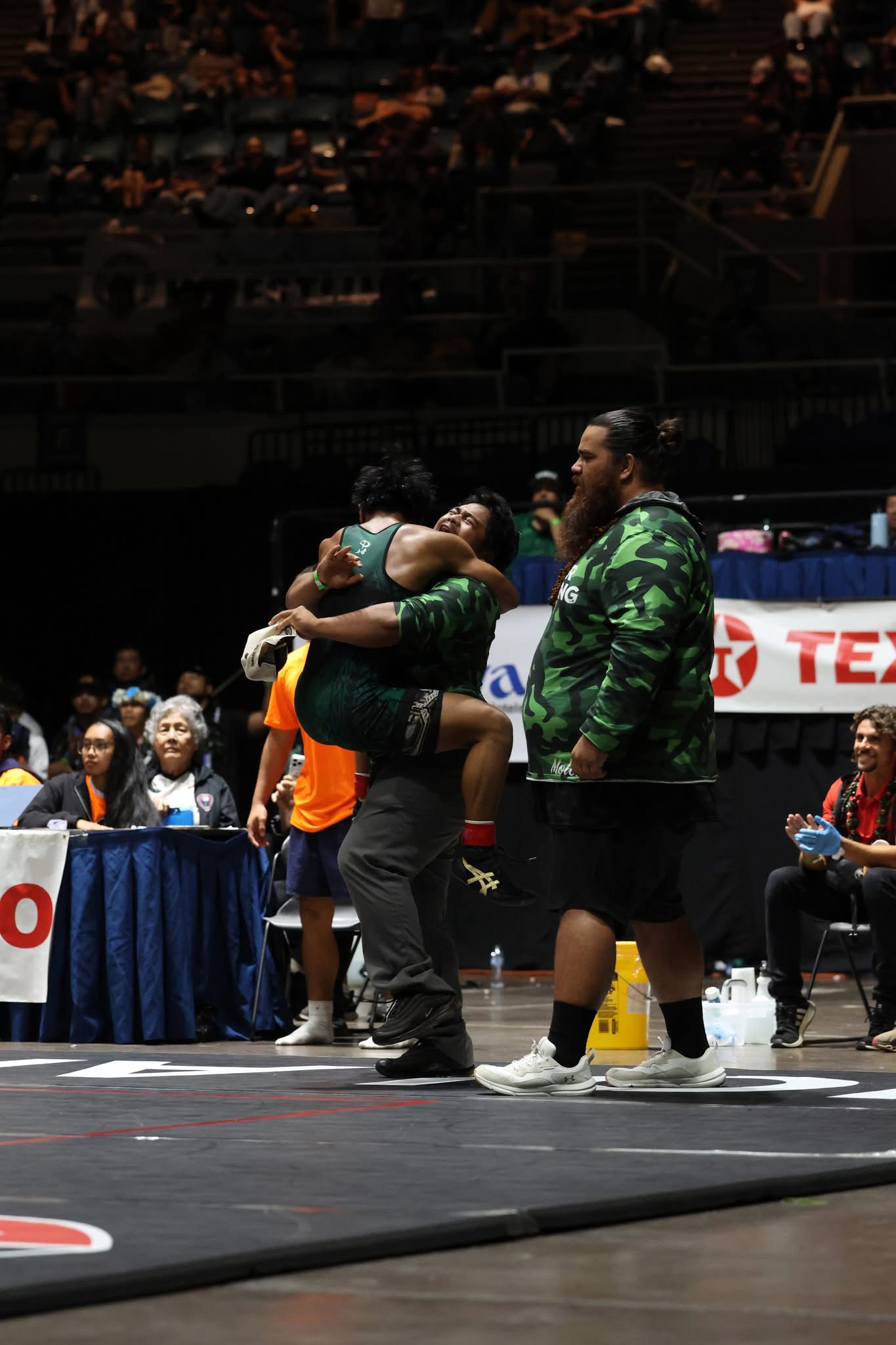 Jona Dudoit of Moloka'i jumps into the arms of his older brother and coach Fatty Dudoit on Saturday after Jona Dudoit won the 126-pound state wrestling championship. Kawika Ka'ahanui is on the right. JASON HAYASE photo