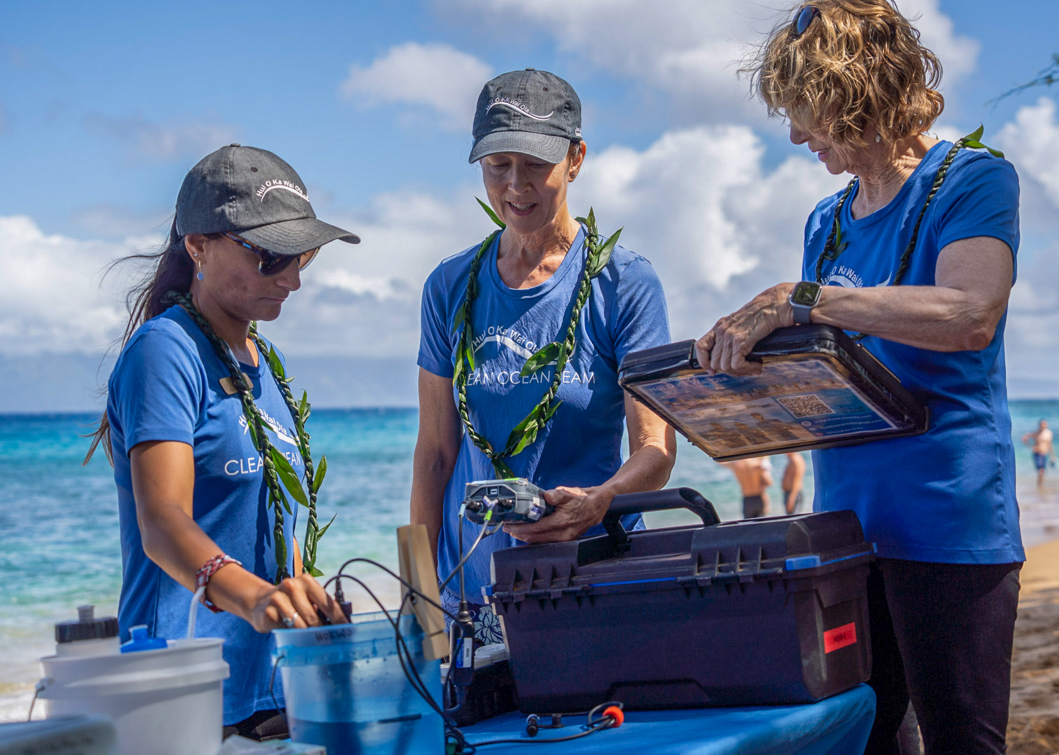 Ylenia Mayen St.-Louis (from left), Kristy Gund and Lyn Hutchings test water samples taken from Kahekili Beach on June 7, 2026. HJI / COLLEEN UECHI photo